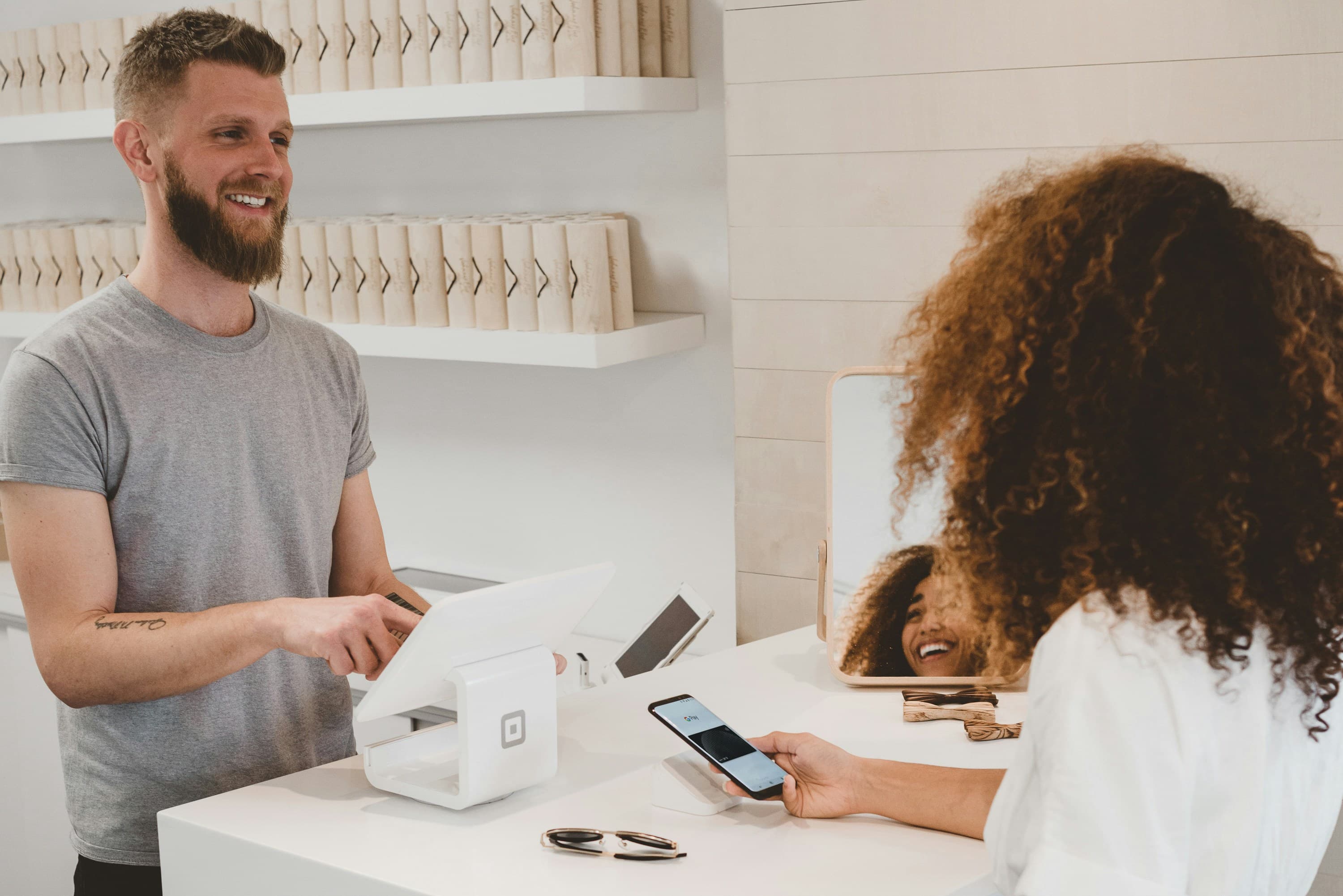 Shop owner serving a smiling customer at the counter